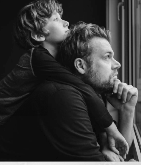 Four black and white photos appear in equal squares, from left to right: a man entering an MRI machine, an infant girl held and holding hands with her mother, a boy leaning on his father’s back, and a young girl lying on an adult’s chest.