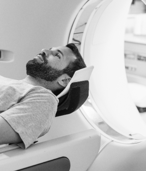 A man with a beard lies on his back about to enter an MRI machine.