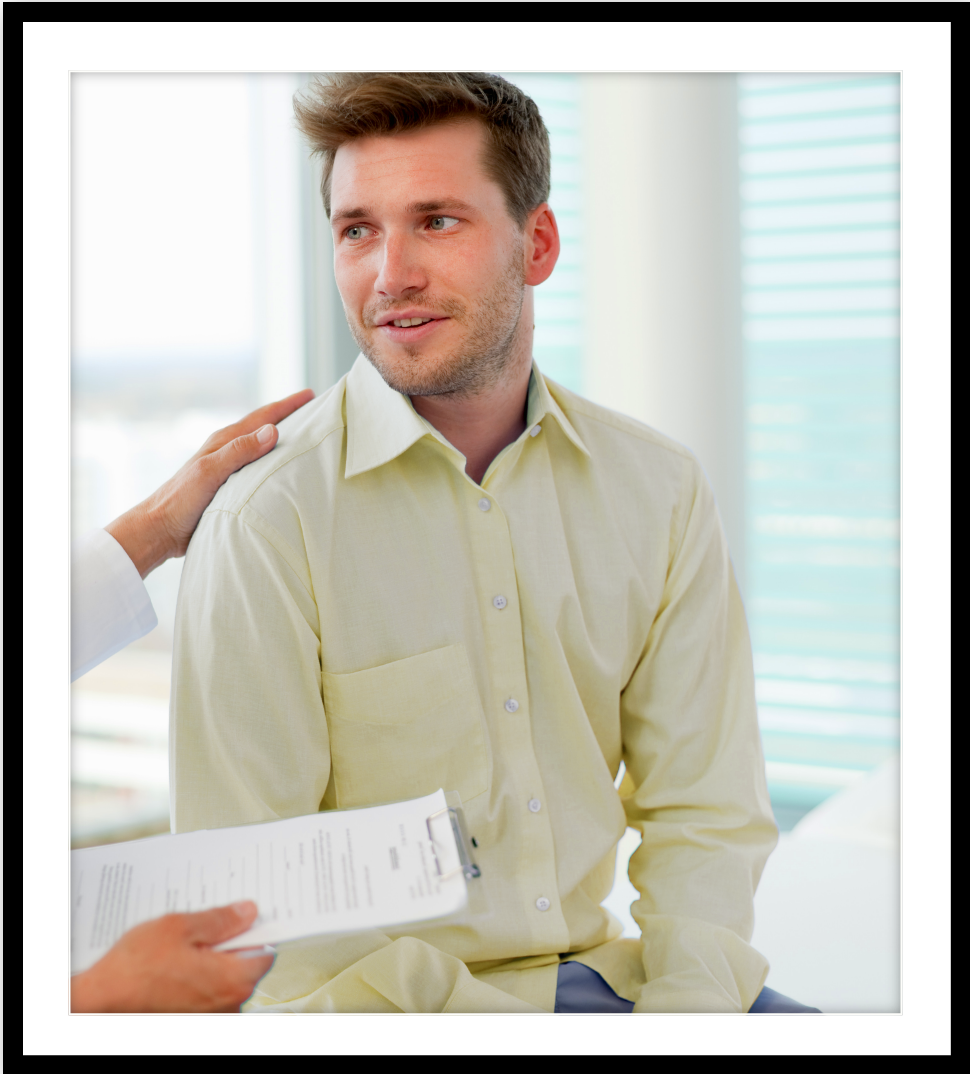 A man with a healthcare provider’s hand on his shoulder.