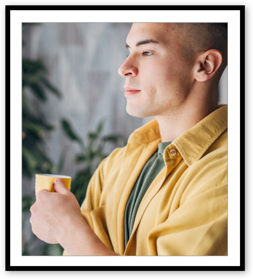 A young man looking thoughtful with a cup in his hand.